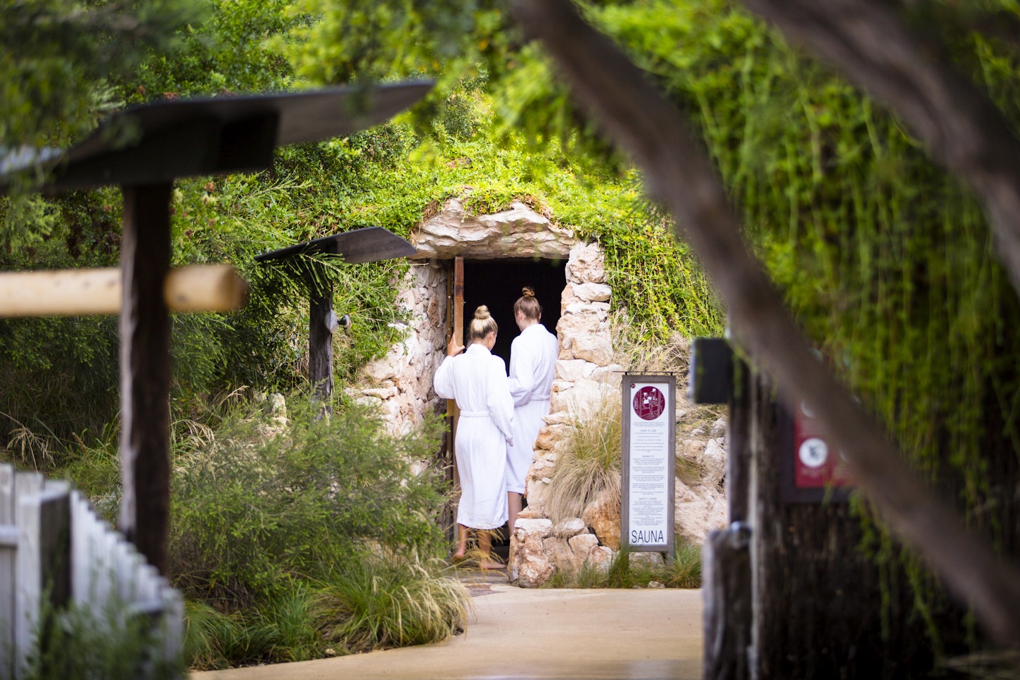 two ladies in white bath robes walking into underground sauna