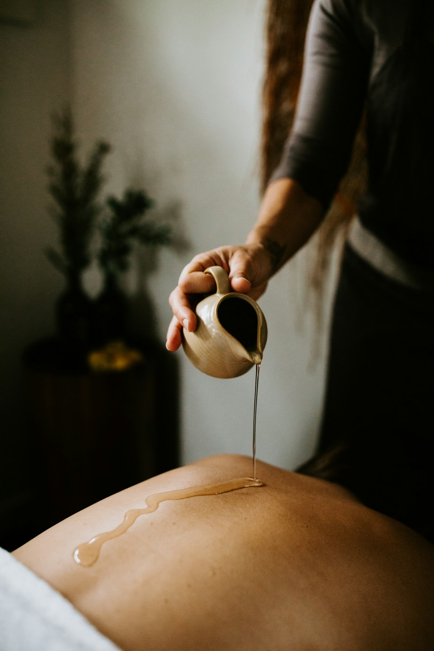 spa therapist pouring treatment oil on lady's back