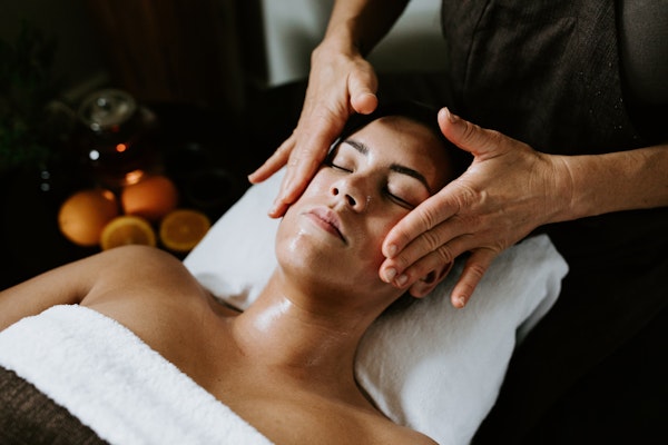 lady lying on treatment bed with eyes closed having face massaged