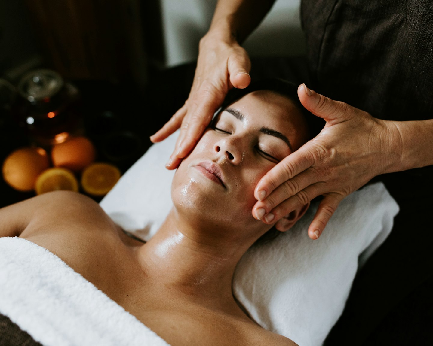 lady lying on treatment bed with eyes closed having face massaged