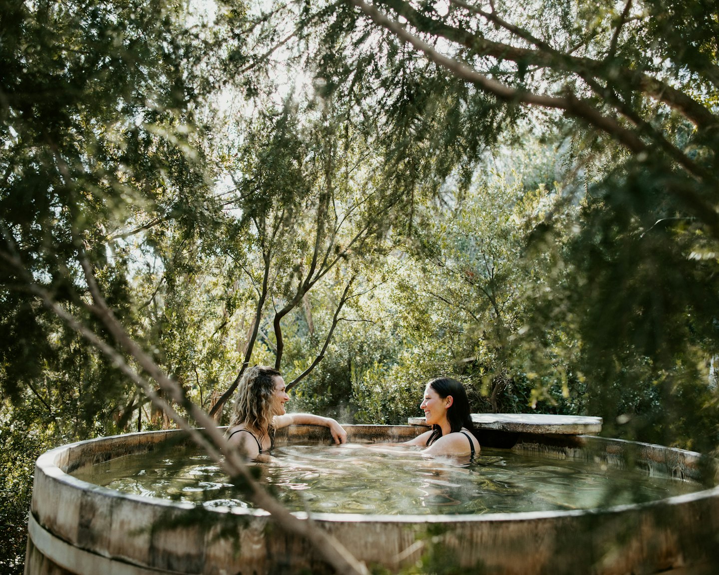 two women sitting and laughing in the barrel pool