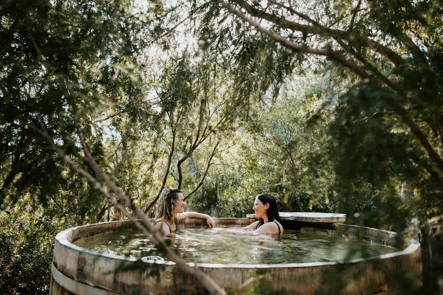 two women sitting and laughing in the barrel pool