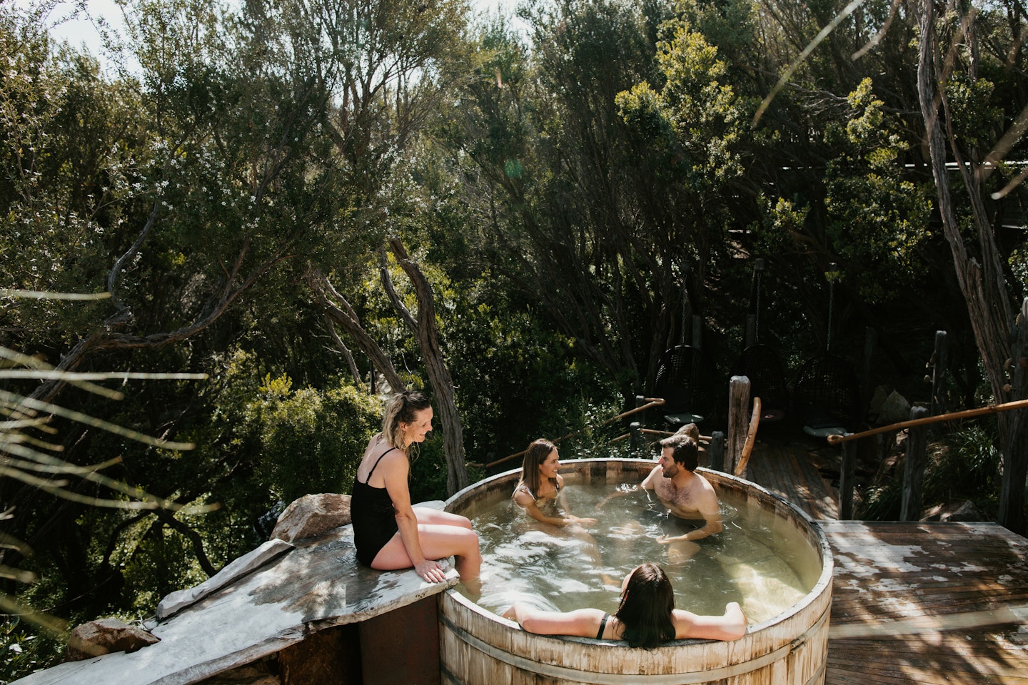 group of friends sitting in a barrel hot pool