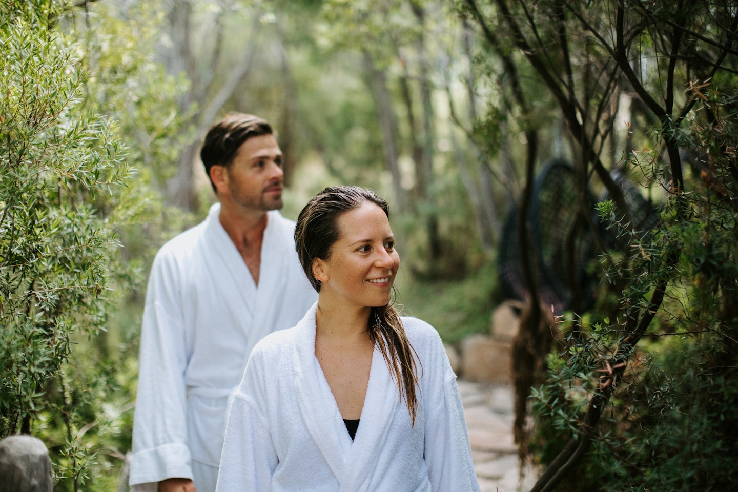 man and woman in white bath robes walking in nature