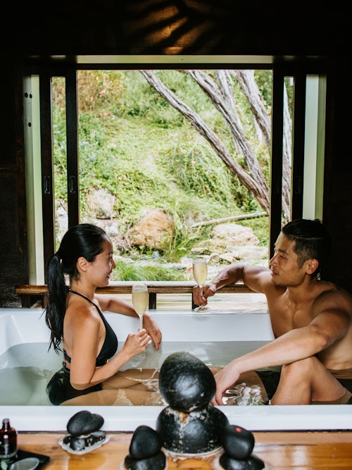couple sitting in private bathing pavilion with glasses of champagne