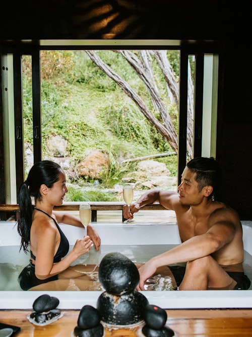 couple sitting in private bathing pavilion with glasses of champagne