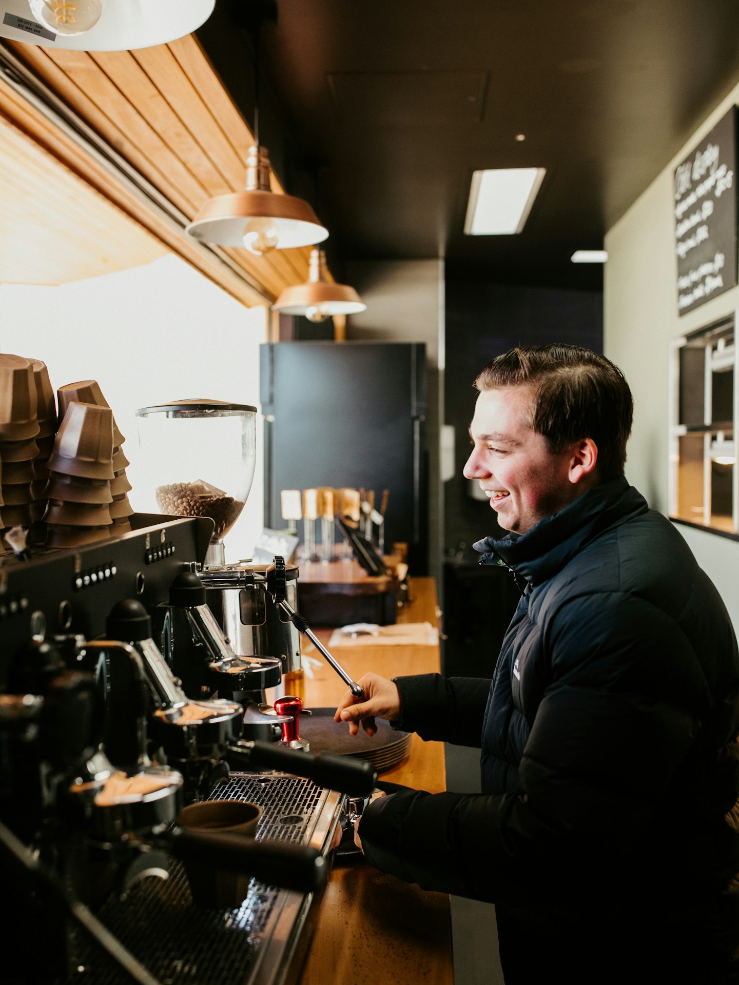barista smiling as he makes coffee for guest