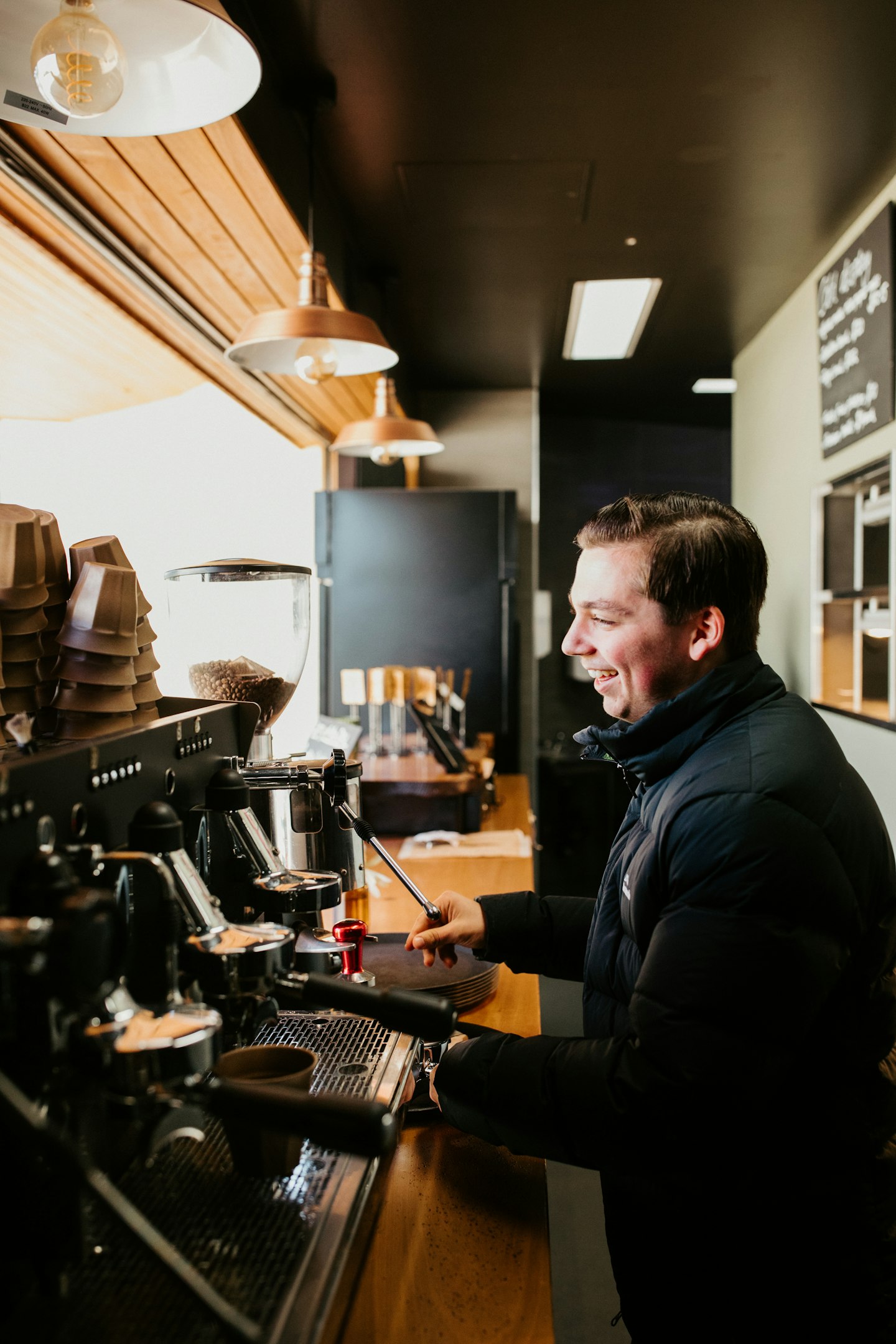 barista smiling as he makes coffee for guest