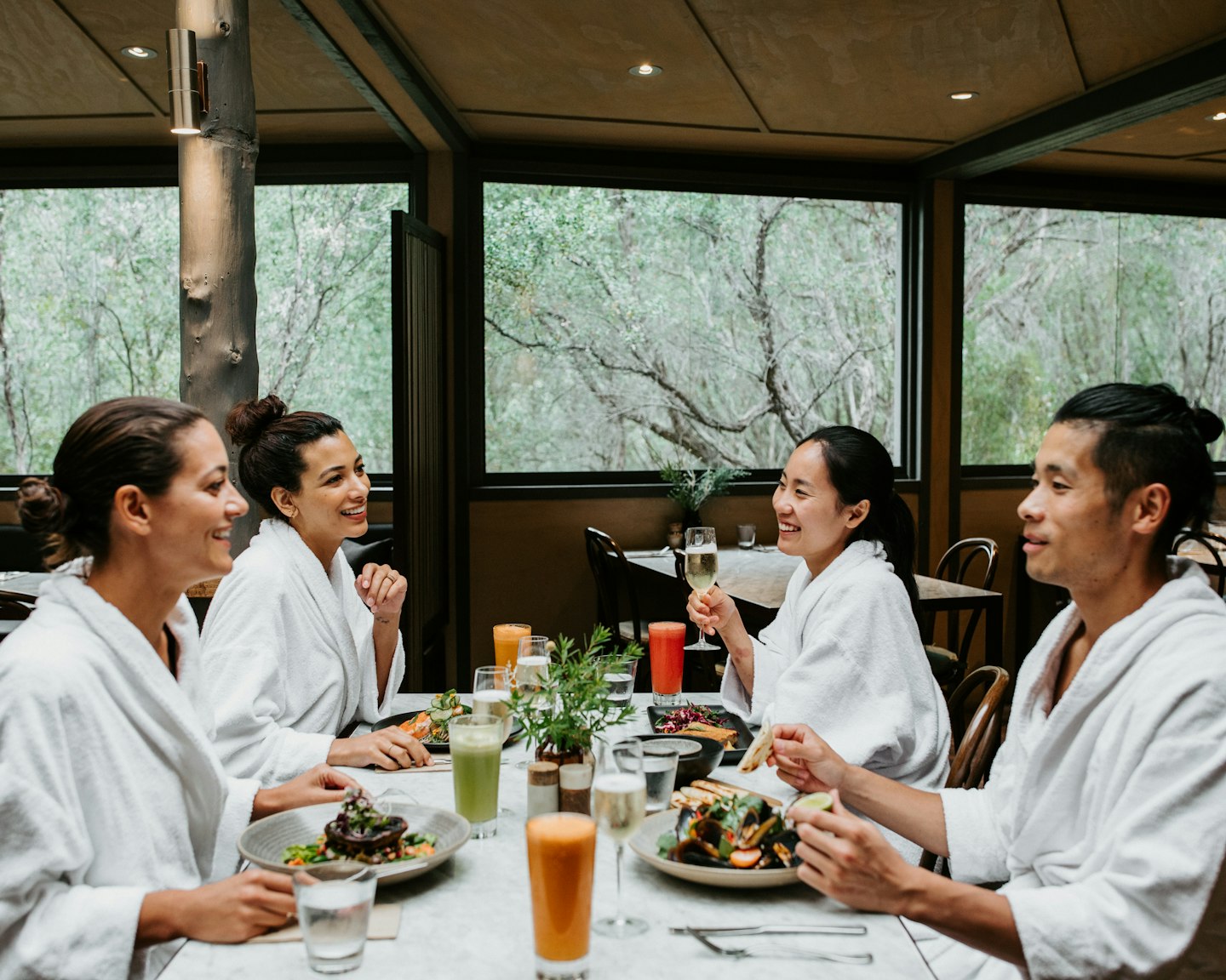 four friends in white bath robes enjoying lunch in restaurant