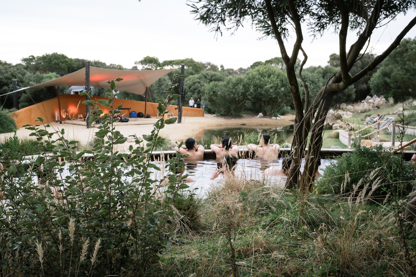 people sitting in geothermal pools listening to live music from amphitheatre stage