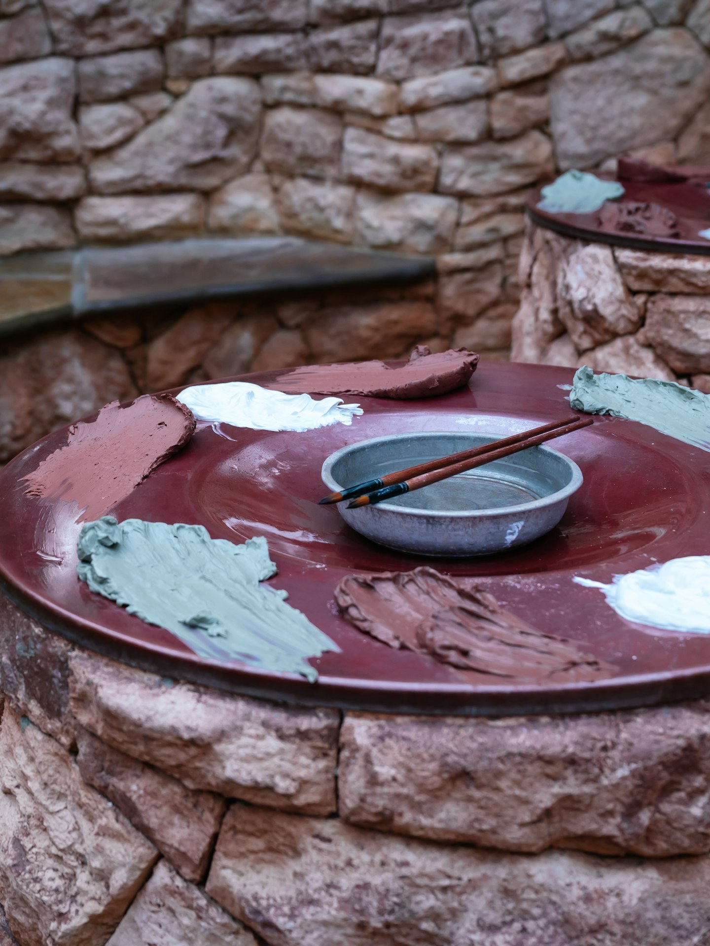 Australian Earth Body Clays and paint brushes laid out on circular pillar ready for guests to paint their skin