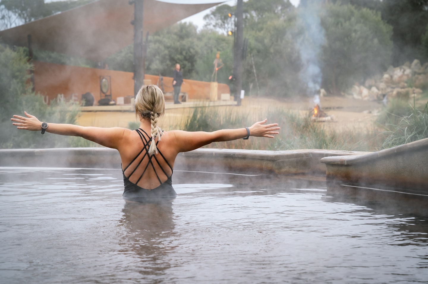 Lady in geothermal pool with arms outstretched in yoga pose