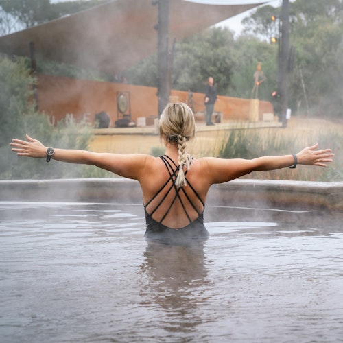 Lady in geothermal pool with arms outstretched in yoga pose