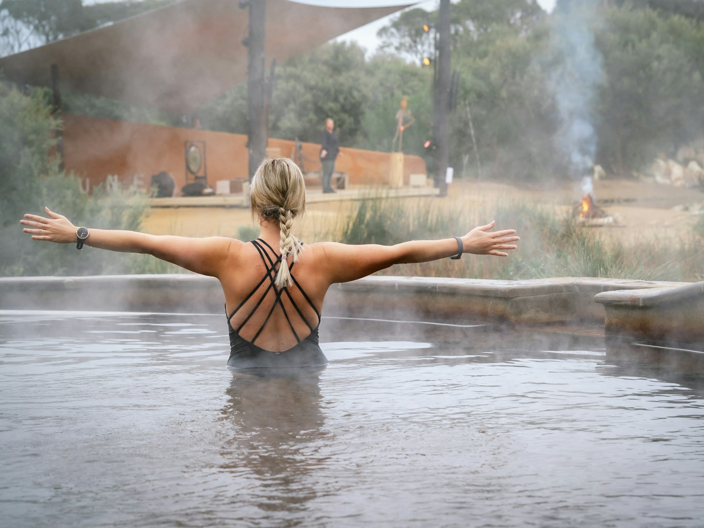 Lady in geothermal pool with arms outstretched in yoga pose