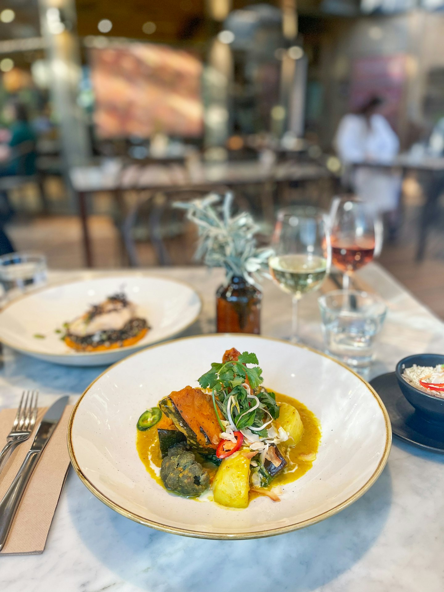 a la carte items from winter restaurant menu on table with glasses of wine in background