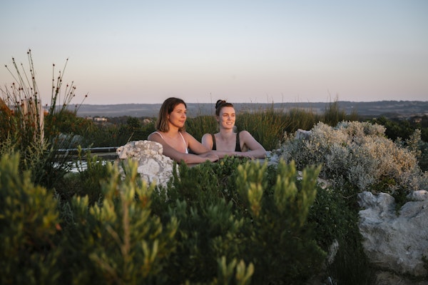 two young women looking out at view from hilltop pool