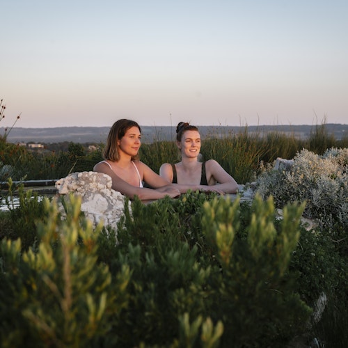 two young women looking out at view from hilltop pool