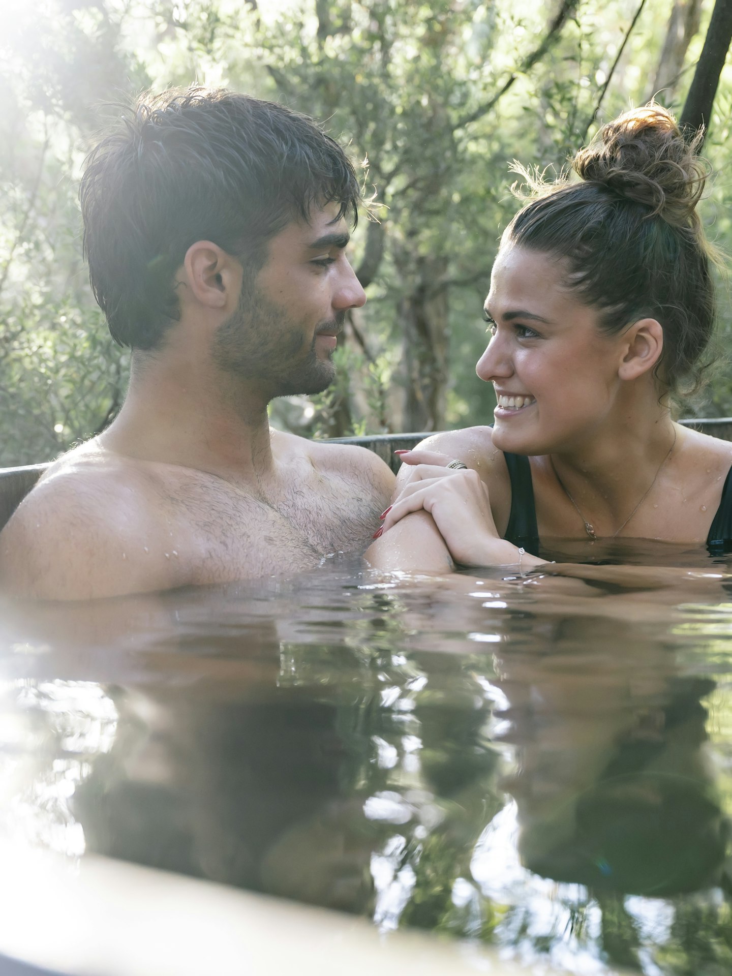 close up of man and woman couple in hot pool looking at one another