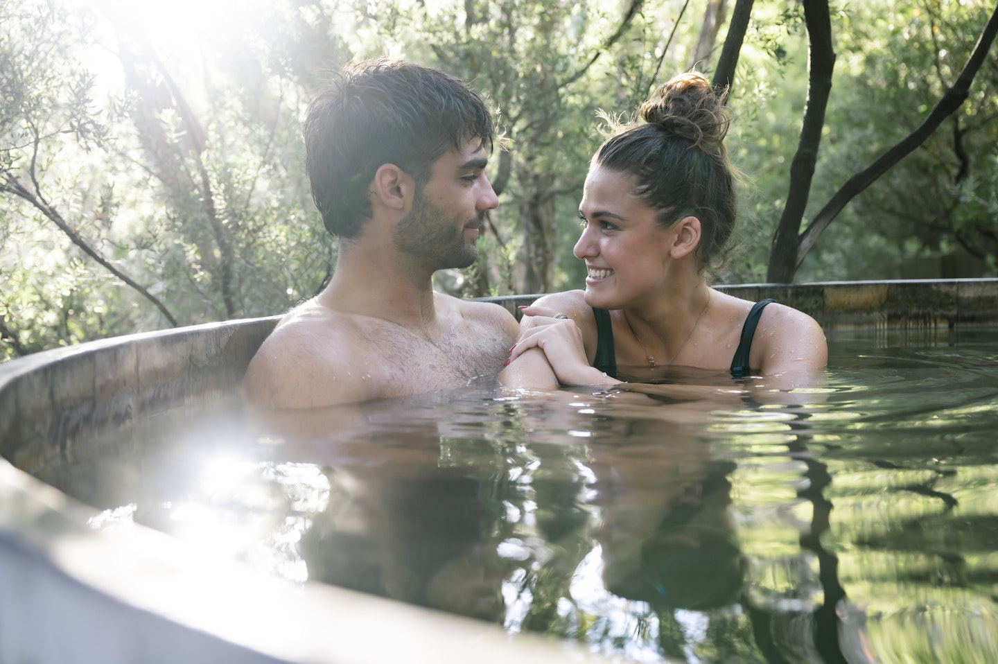 close up of man and woman couple in hot pool looking at one another