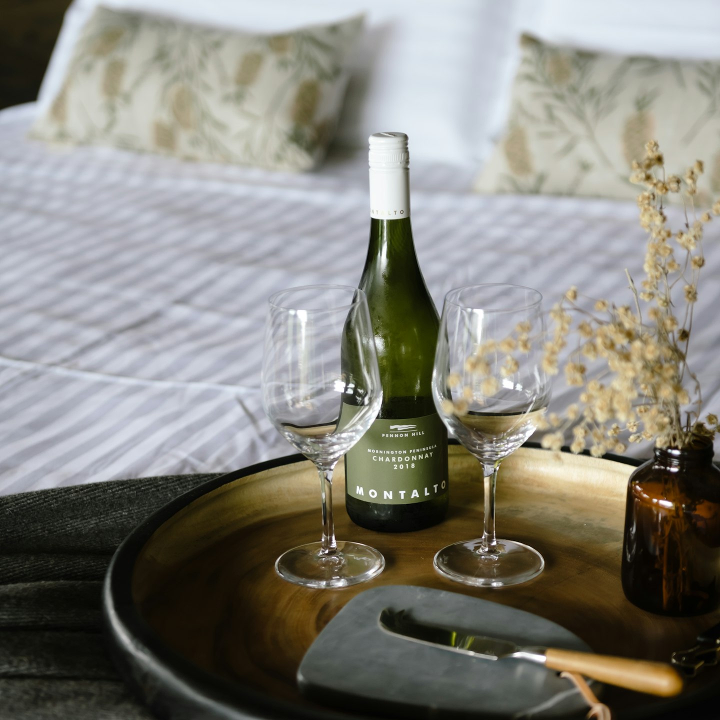 tray on beautifully styled bed with wine, wine glasses and native flowers in glass vase