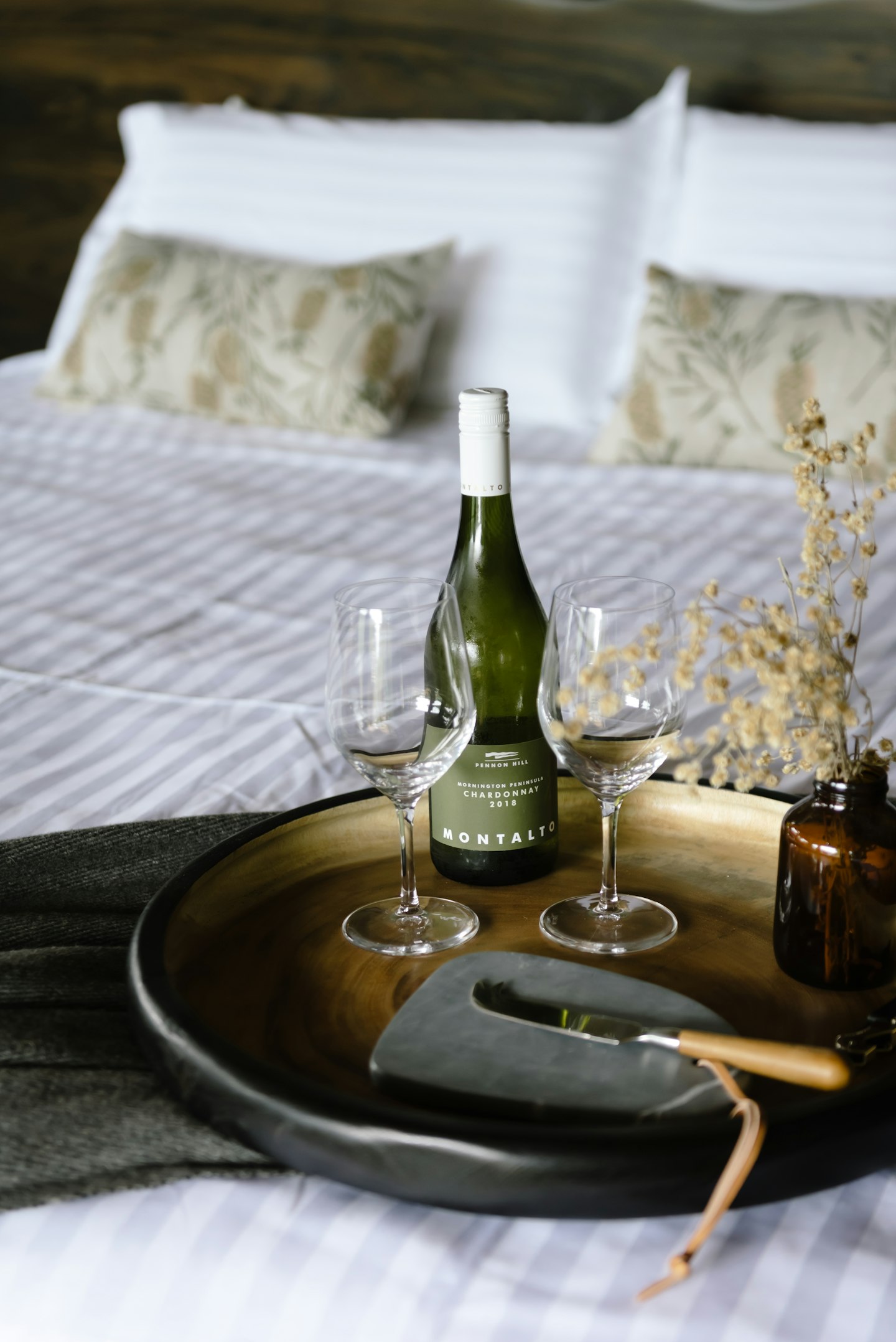 tray on beautifully styled bed with wine, wine glasses and native flowers in glass vase