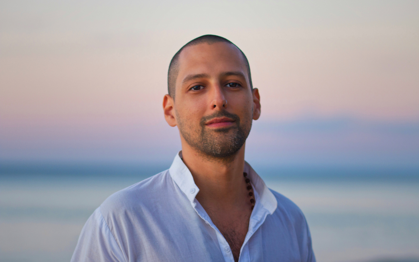 man looking at camera with blurry ocean behind him