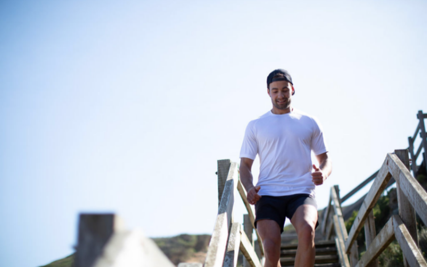 fitness man running down beachside stairs