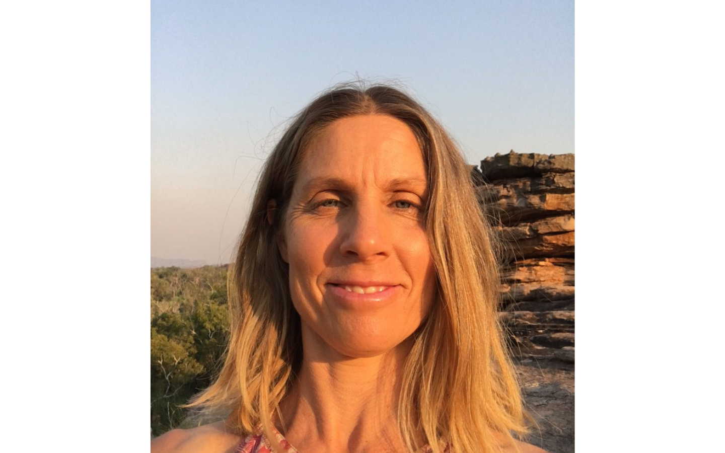 woman looking into camera with rock formations and trees in background