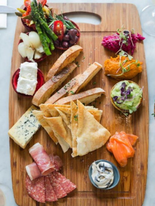 grazing board with cheese, dip, charcuterie, smoked salmon, dip, breads, olives