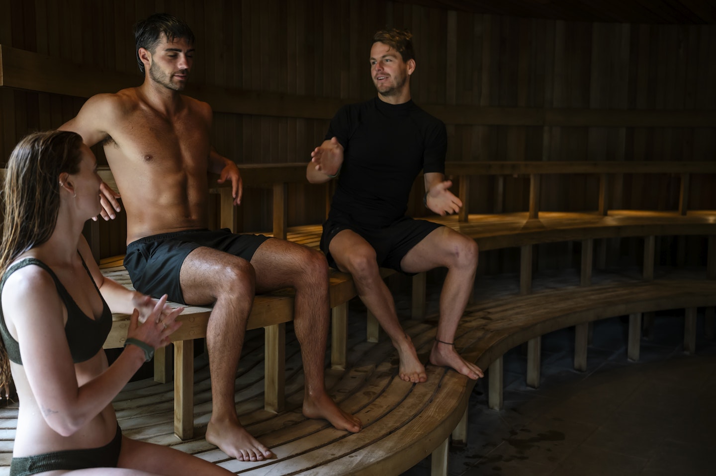 instructor explaining information to man and woman sitting on wooden benches in sauna