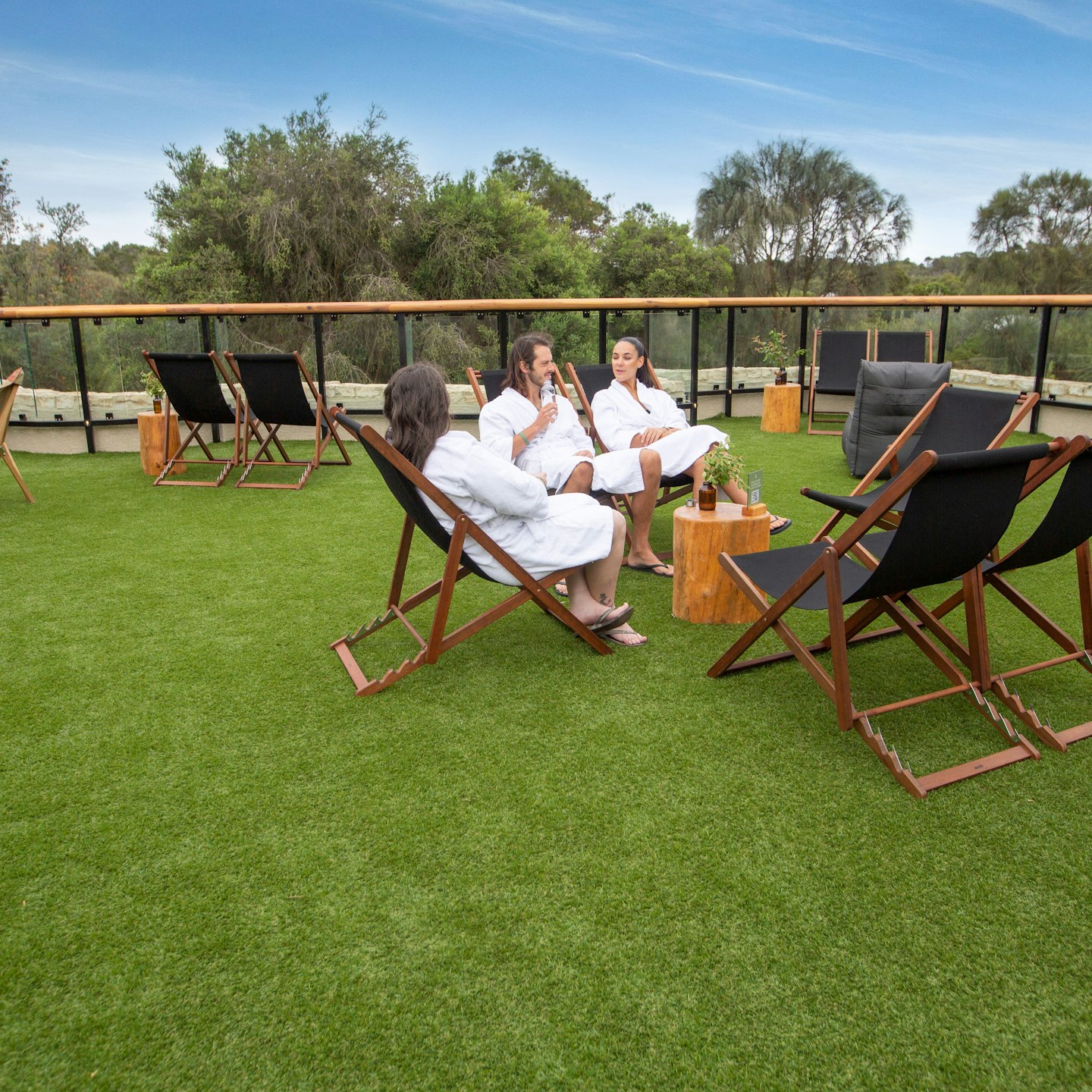 three people sitting on deck chairs on expansive, grassed sun lounge