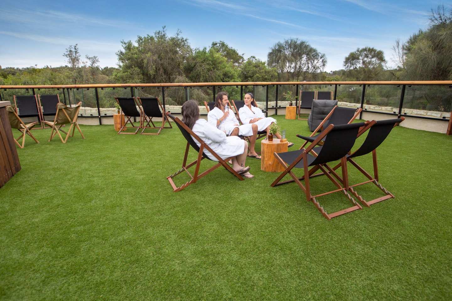 three people sitting on deck chairs on expansive, grassed sun lounge
