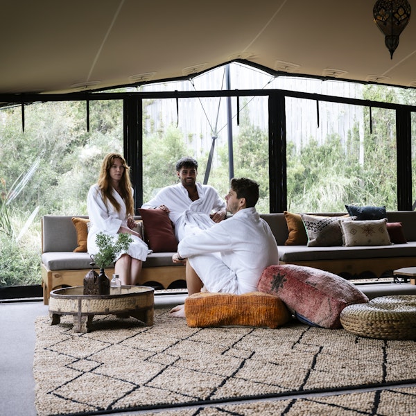 three adults in white bath robes sitting on couches and floor cushions in Moroccan Pavilion