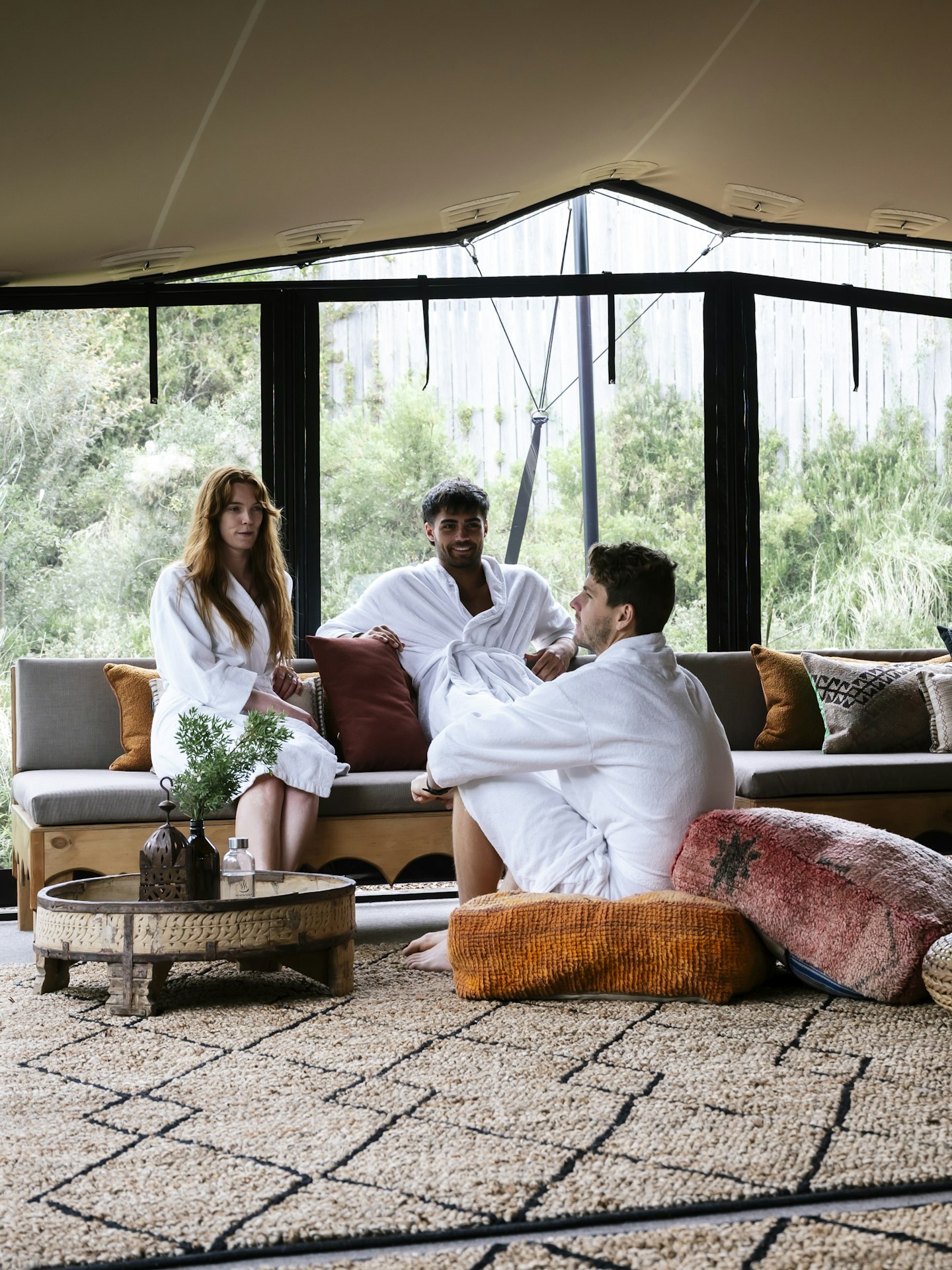 three adults in white bath robes sitting on couches and floor cushions in Moroccan Pavilion