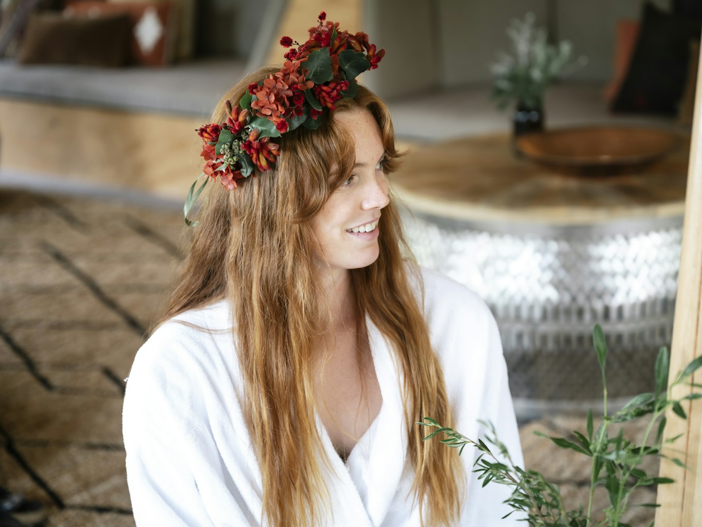girl with wildflower crown on her head wearing white bath robe sits smiling in moroccan pavilion
