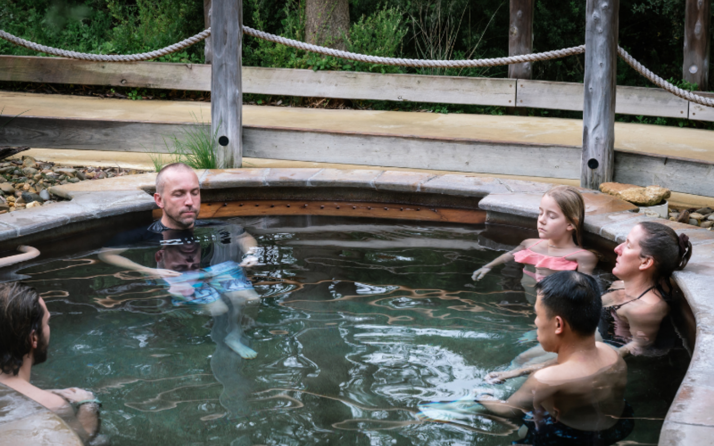 Five people sitting in bath house pool with their eyes closed