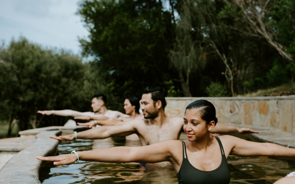 four people practicing hot springs yoga in an amphitheater pool