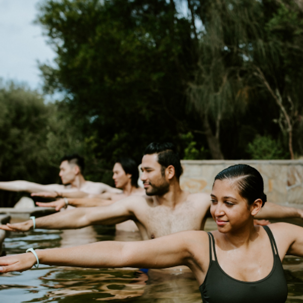 four people practicing hot springs yoga in an amphitheater pool