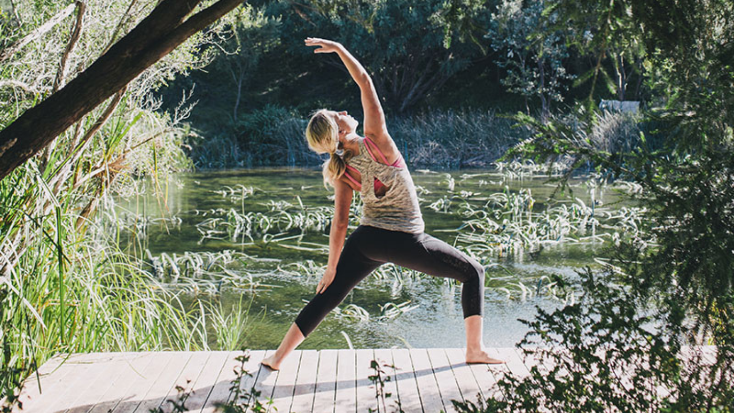 girl in a warrior yoga pose on a bridge
