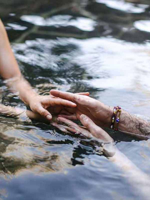 man and woman holding outstretched hands in geothermal waters