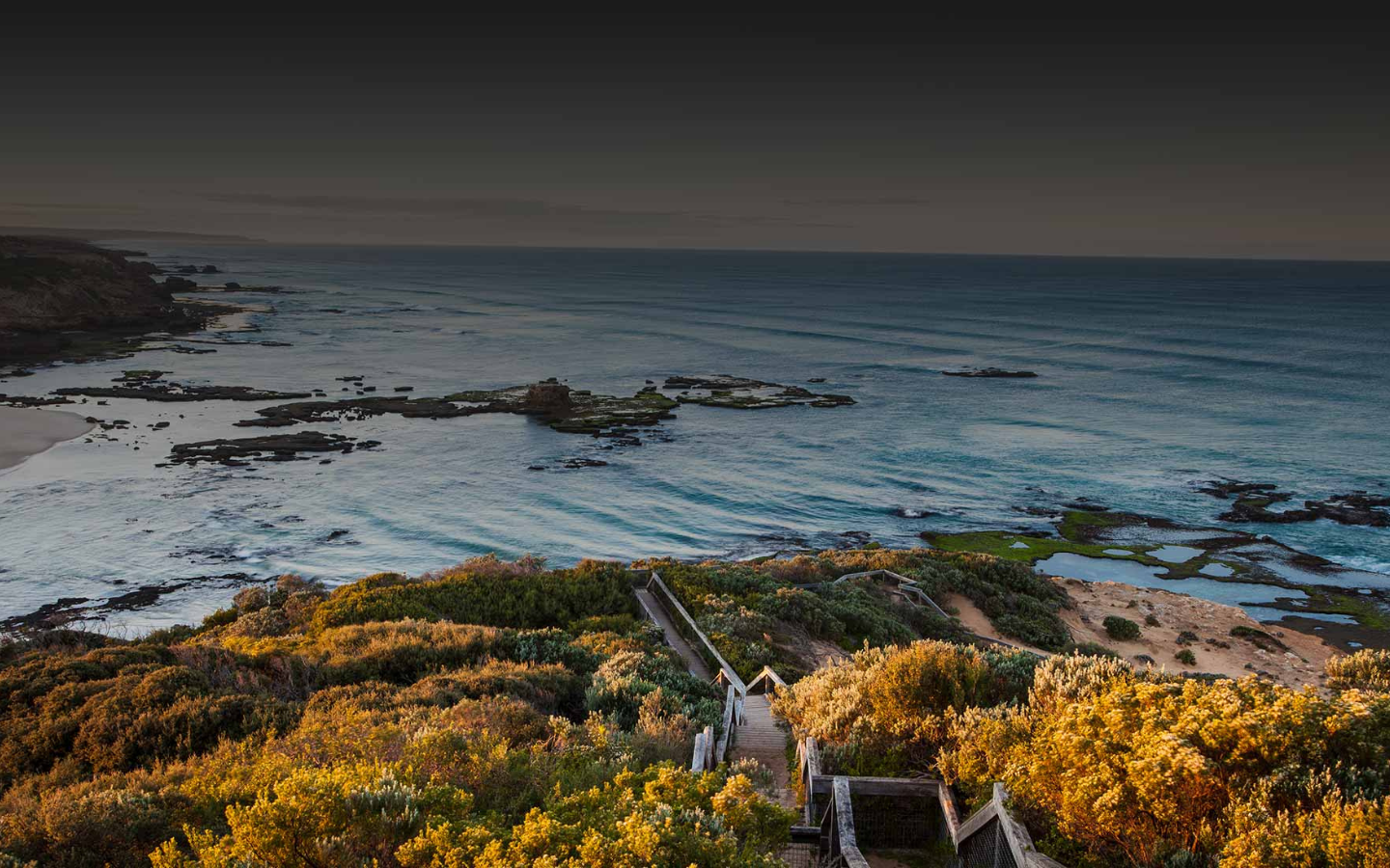 view of mornington peninsula beach with wooden stairs leading down to water