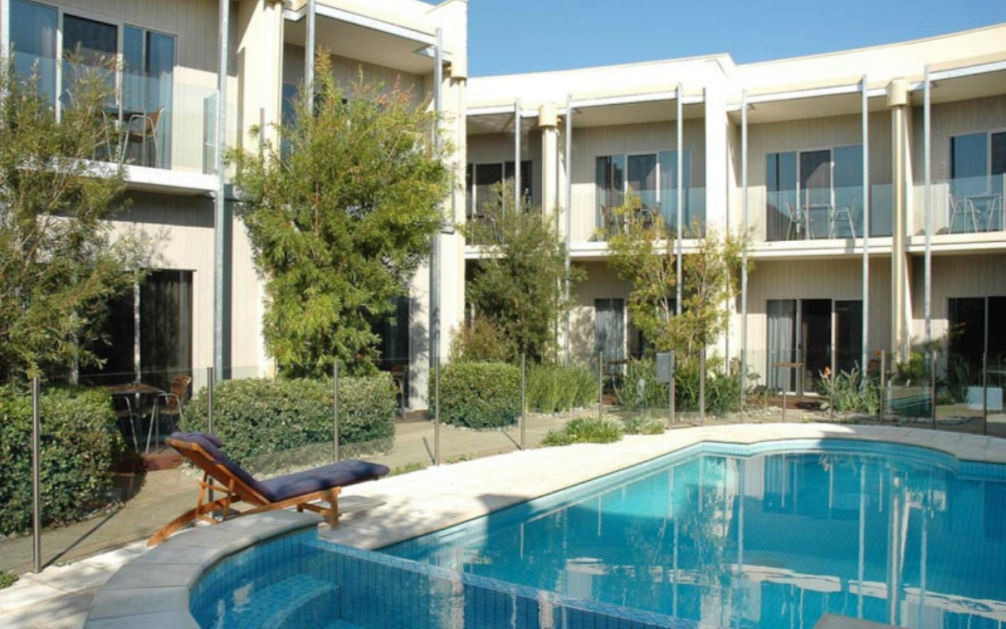 view of hotel rooms overlooking inground pool