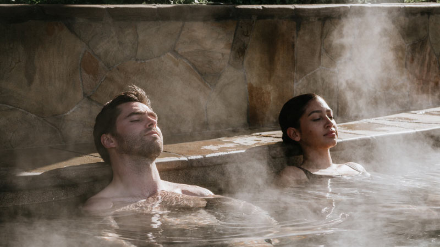 couple relaxing with eyes closed in steamy bath house amphitheatre pool