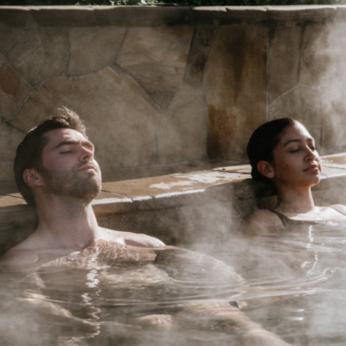 a man and woman relaxing with their eyes closed in an amphitheater hot spring