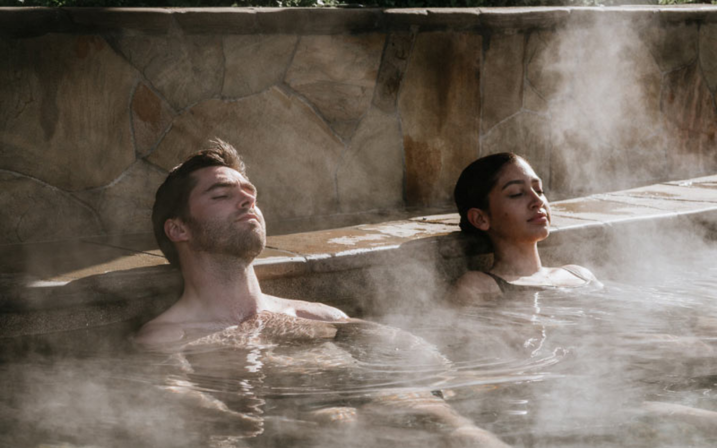 couple relaxing with eyes closed in steamy bath house amphitheatre pool