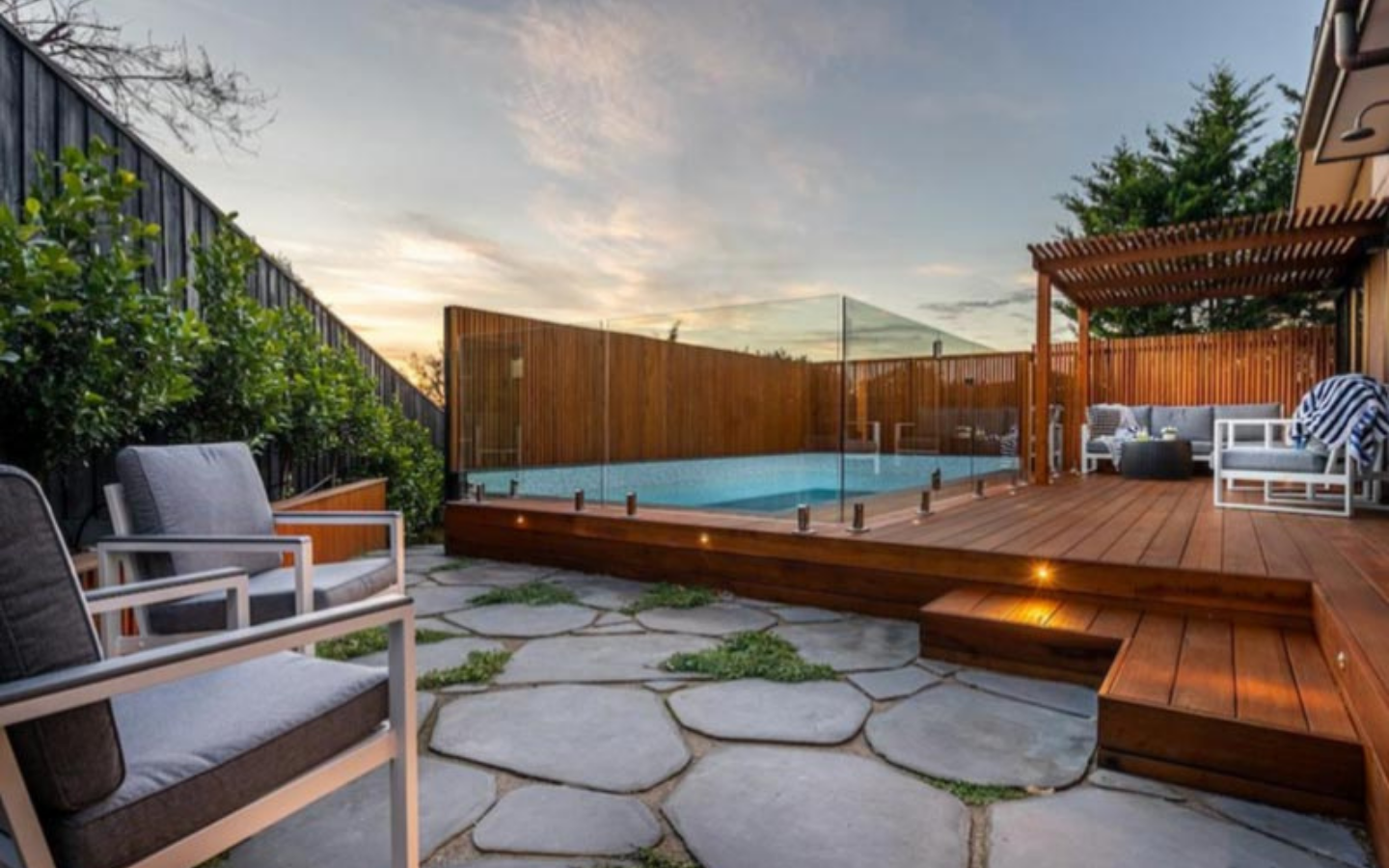 paved area with chairs and decked area with inground pool