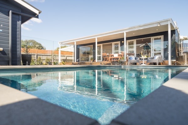 view of inground pool looking up to beach house exterior