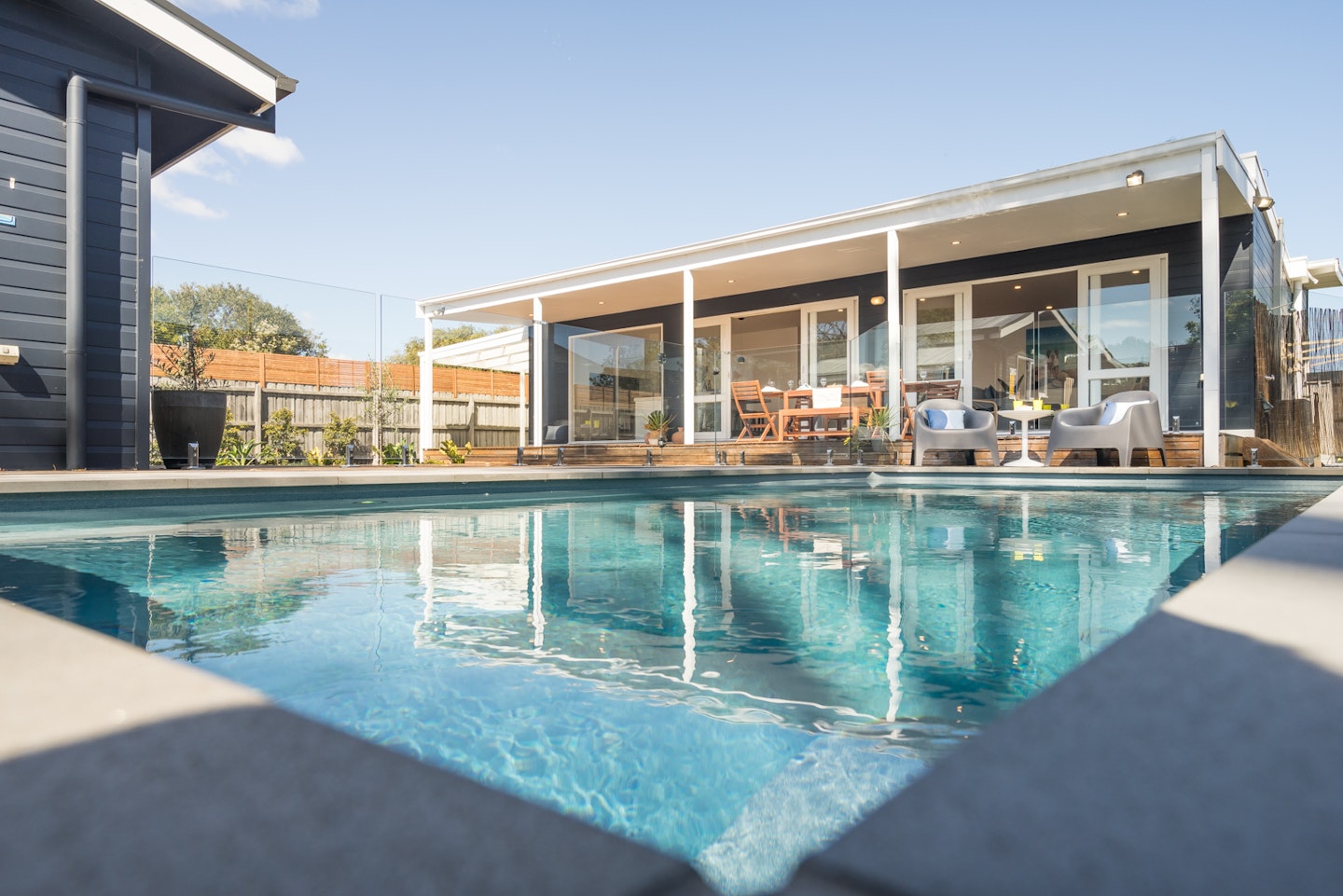 view of inground pool looking up to beach house exterior