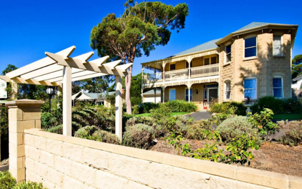 external view of grand sandstone home with manicured gardens