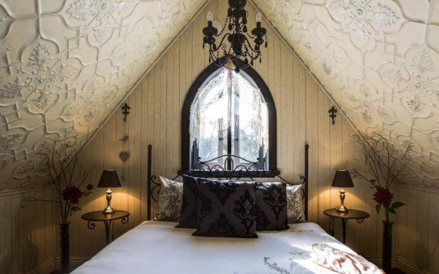 wrought iron bed with chandelier and pressed metal ceilings